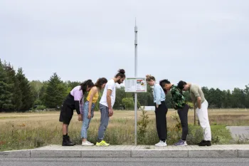 Personen lehnen an einer Bushaltestelle als Performance